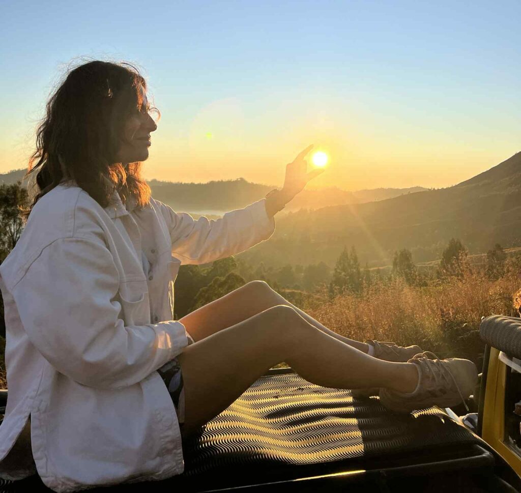 Holistic coach sitting on a car roof on sunset